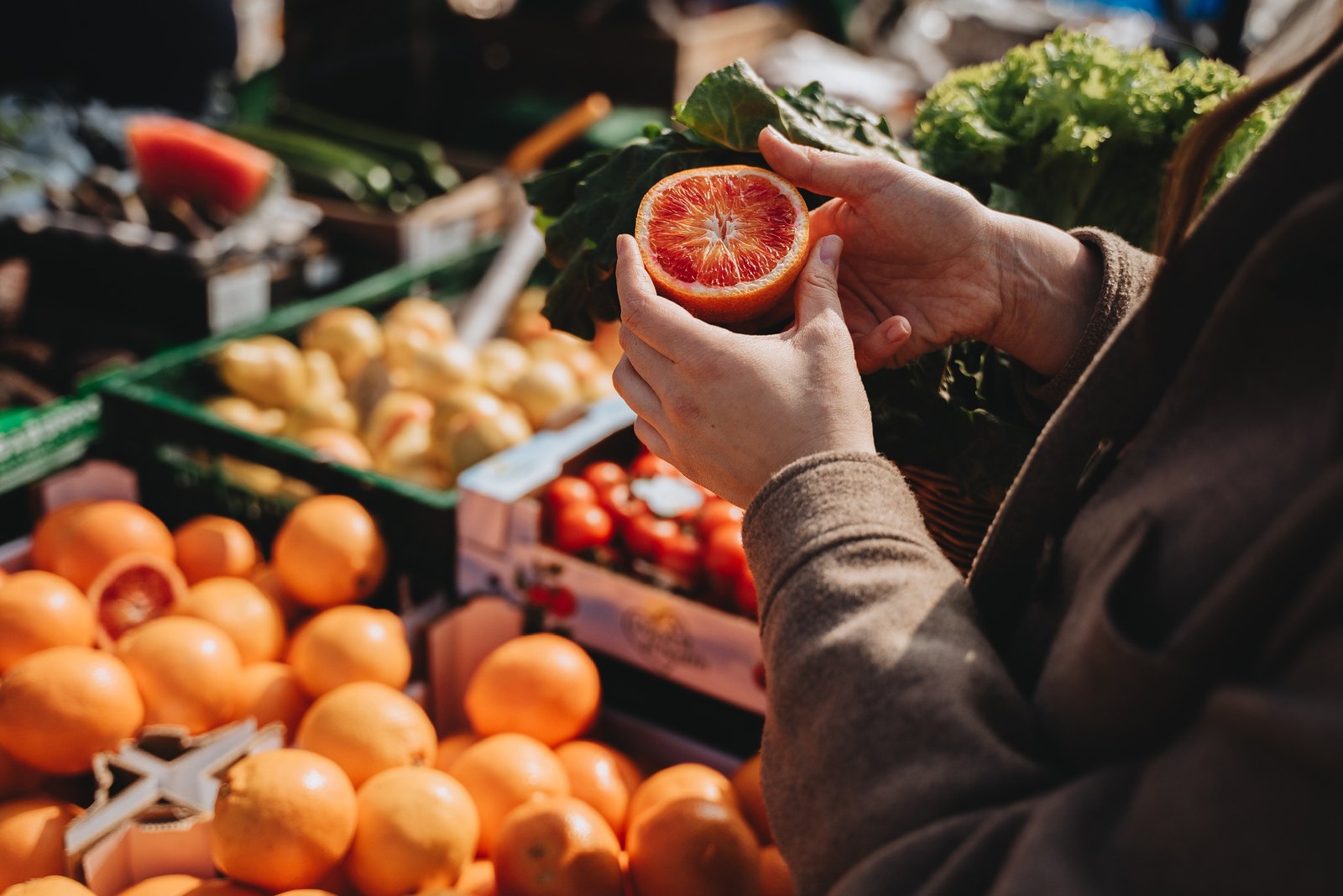 person inspecting a halved orange in a market